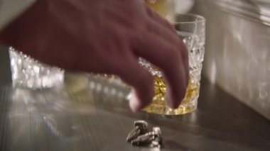 Bir adamın eline yakın plan bir bardak alkol alır. Renk düzeltmesi olmadan, film kalitesi olmadan. Yüz tanıma olmadan yakın plan.