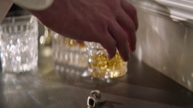 Bir adamın eline yakın plan bir bardak alkol alır. Renk düzeltmesi olmadan, film kalitesi olmadan. Yüz tanıma olmadan yakın plan.