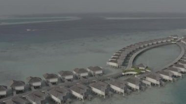 Sudaki bir bungalov villasının havadan görünüşü. Tropik Maldivler 'deki egzotik bir turkuaz cennetinin insansız hava aracı görüntüleri. Yüksek kaliteli 4K video. Maldivler 'de lüks bir tatil köyü. Renk düzeltmesi olmayan görüntü.