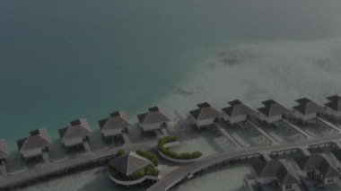 Sudaki bir bungalov villasının havadan görünüşü. Tropik Maldivler 'deki egzotik bir turkuaz cennetinin insansız hava aracı görüntüleri. Yüksek kaliteli 4K video. Maldivler 'de lüks bir tatil köyü. Renk düzeltmesi olmayan görüntü.