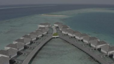 Sudaki bir bungalov villasının havadan görünüşü. Tropik Maldivler 'deki egzotik bir turkuaz cennetinin insansız hava aracı görüntüleri. Yüksek kaliteli 4K video. Maldivler 'de lüks bir tatil köyü. Renk düzeltmesi olmayan görüntü.