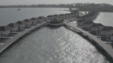 Sudaki bir bungalov villasının havadan görünüşü. Tropik Maldivler 'deki egzotik bir turkuaz cennetinin insansız hava aracı görüntüleri. Yüksek kaliteli 4K video. Maldivler 'de lüks bir tatil köyü. Renk düzeltmesi olmayan görüntü.