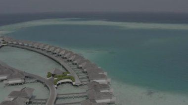 Sudaki bir bungalov villasının havadan görünüşü. Tropik Maldivler 'deki egzotik bir turkuaz cennetinin insansız hava aracı görüntüleri. Yüksek kaliteli 4K video. Maldivler 'de lüks bir tatil köyü. Renk düzeltmesi olmayan görüntü.