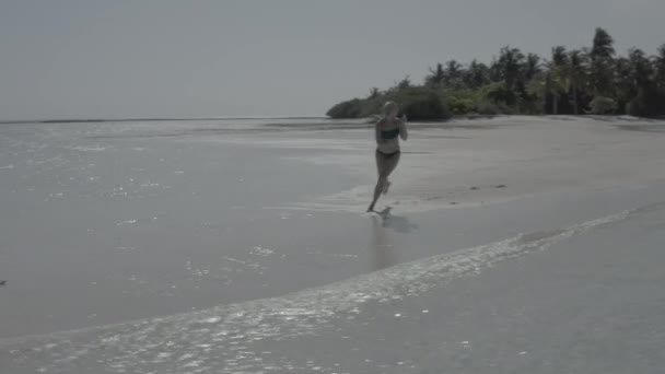 在奇异的热带马尔代夫 快乐快乐的女孩在沙滩上跳跃 在海滩上开心地笑着 享受阳光和清澈清澈的海水 无色彩校正的图像 — 图库视频影像