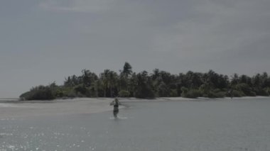 Egzotik tropik Maldivler 'in kumlu sahilinde atlayan neşeli kız. Gülümseyen neşeli bayan sahilde eğleniyor, güneşin ve berrak suyun tadını çıkarıyor. Renk düzeltmesi olmayan görüntü.