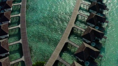 Mavi göldeki, beyaz kumlu sahildeki lüks villaların havadan görünüşü. Maldivler 'de sıralanmış su üzerinde bungalovları olan bir ada..