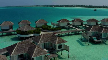 Mavi göldeki, beyaz kumlu sahildeki lüks villaların havadan görünüşü. Maldivler 'de sıralanmış su üzerinde bungalovları olan bir ada..