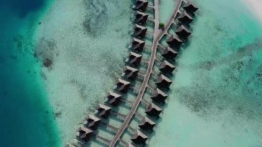 Mavi göldeki, beyaz kumlu sahildeki lüks villaların havadan görünüşü. Maldivler 'de sıralanmış su üzerinde bungalovları olan bir ada..