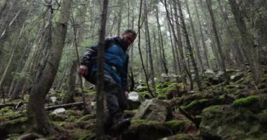Dağda bir genç adam, sisli bir ormanda ağaçların arasında sırt çantasıyla yürüyüş yapıyor. Uzun havada tek bir yürüyüş..