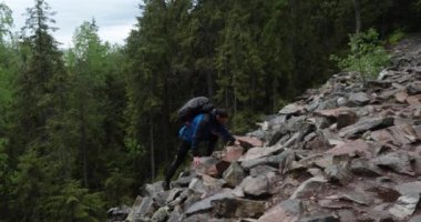 Bir adam, bulutlu havada dağlık bir ormanda yürüyüş yapan kayalık arazide yürüyen bir yürüyüşçüdür. Dağlarda tek bir yürüyüş.