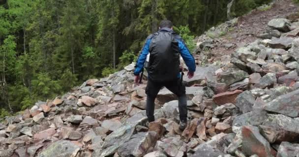 曇りの日に岩の多い地形を歩く山の森のハイキング中のハイカーです 山の中のシングルハイキング — ストック動画