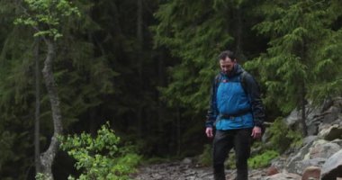 Formda bir genç adam kayalık bir arazide tek başına yürüyor, ormandan çıkıyor. Yalnız seyahat eden bir adam konsepti..