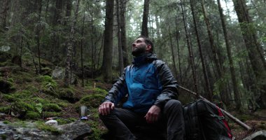 Bir gezgin yağmurlu havada ormanda bir gaz ocağında çay hazırlar. Yalnız bir gezgin metal bir kupadan çay hazırlar ve içer.