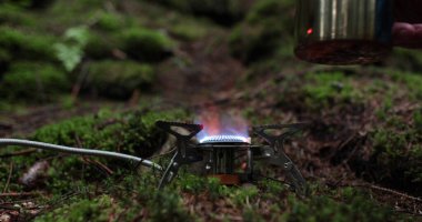 Metal bardak, bir gezginin tatili sırasında ormanda gaz ocağında ısıtılır. Tek başına çay yapma kavramı..