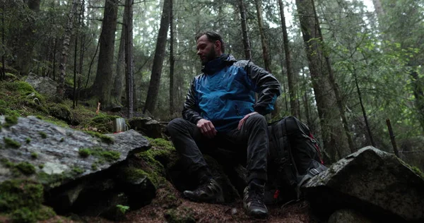 stock image A traveler prepares tea on a gas burner in the forest in rainy weather. A lone traveler prepares and drinks tea from a metal mug