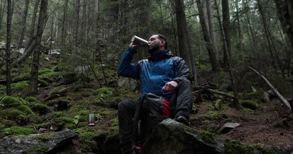 Молодой Путешественник Пьет Воду Металлической Бутылки Сидя Лесу Камне Дождливую — стоковое фото