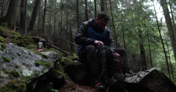 Młody Podróżnik Pije Wodę Metalowej Butelki Siedząc Lesie Kamieniu Deszczową — Wideo stockowe