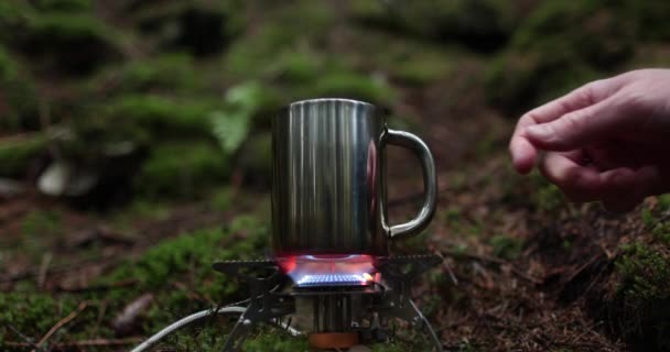 在旅行的过程中 在自然森林里的煤气炉上加热 在金属壶中加入茶叶 在一个孤独的旅行者的独行旅程中泡茶 — 图库视频影像