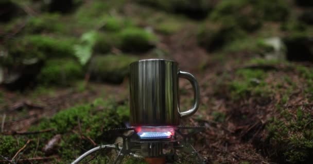 旅行者度假时 一个金属杯子在森林里的煤气炉上加热 独游时泡茶的概念 — 图库视频影像