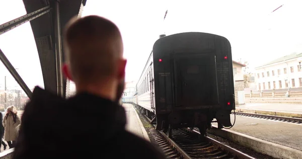 一个年轻人看着一列火车离开车站 一个看着火车从火车站开出的年轻人的画像 — 图库照片