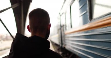 Genç bir adam istasyondan ayrılan treni izliyor. Tren istasyonundan kalkan trene bakan genç bir adamın portresi..