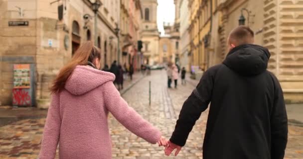 若くて美しく 愛するカップルが街の通りで暗い秋の日を歩き 手を握り 微笑み キスして話す — ストック動画