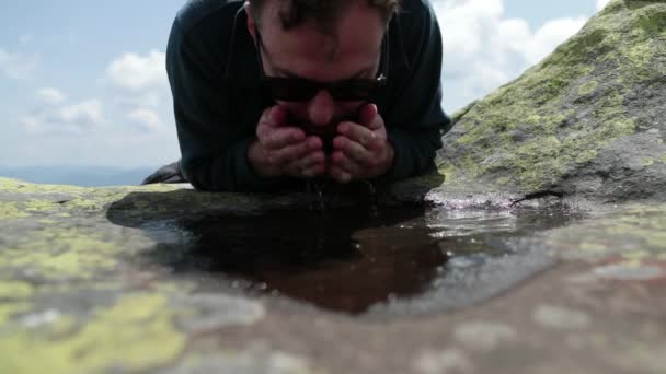 一个又渴又健康的游客跑上来 在恶劣的山区条件下从一个小水坑里喝水 山区生存概念 在山穷水尽的山穷水尽 — 图库视频影像