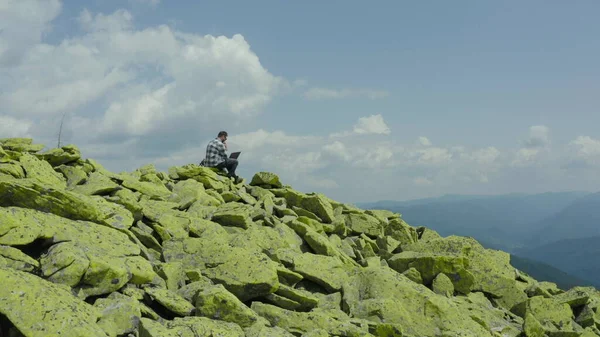Homem Trabalha Laptop Enquanto Está Sentado Topo Uma Montanha Rochosa — Fotografia de Stock
