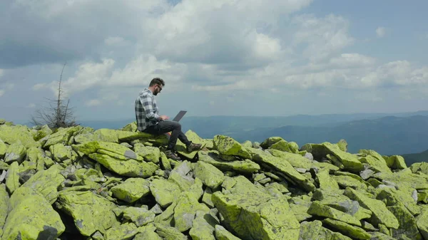 Человек Работает Ноутбуке Сидя Вершине Скалистой Горы Удаленная Работа Отпуске — стоковое фото