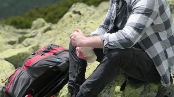 一个人坐在岩石斜坡上喝瓶子里的水 徒步旅行时 一个人喝瓶子里的水 在山上一次远足 — 图库视频影像