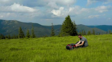 Erkek bir turist dinlenmek için mola verir ve dağlarda tek başına yürüyüş yaparken su içer..
