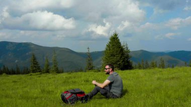 Erkek bir turist dinlenmek için mola verir ve dağlarda tek başına yürüyüş yaparken su içer..