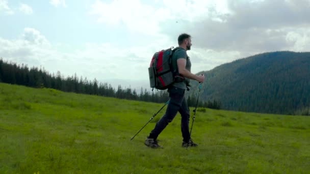 Mężczyzna Górach Plecakiem Plecach Spaceruje Trawiastym Zboczu Piękny Letni Dzień — Wideo stockowe