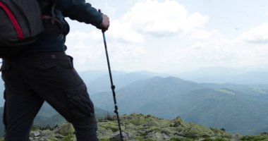 Dağlara bir gezi, bir turist sırt çantası ve çubuklarla gider, yüksek dağların kayalık arazisinde seyahat eder, bağımsız, kayalıklarda yalnız gezer..