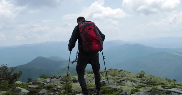 山での旅行 観光客はバックパックとスティックと一緒に行く 高山の岩の地形を旅します 独立した 岩の上の孤独なハイカー — ストック動画