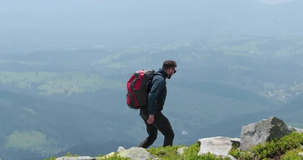 中年のバックパッカーの男性は 信じられないほどの景色でゆっくりと山の端に近づきます 高山でのソロハイキングのコンセプト — ストック写真