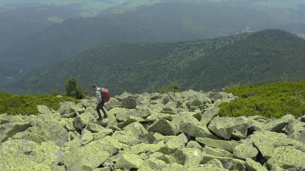 男は巨大な石で覆われた山の斜面に沿って歩いています ツーリスト ハードハイキング アドベンチャーツーリズムのコンセプト — ストック写真