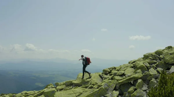 男は巨大な石で覆われた山の斜面に沿って歩いています ツーリスト ハードハイキング アドベンチャーツーリズムのコンセプト — ストック写真