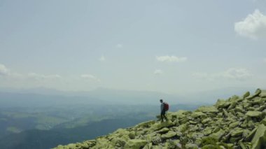 Dev taşlarla kaplı bir dağ yamacı boyunca yürüyen bir adam. Solo turizm. Zor yürüyüş, macera turizmi konsepti.