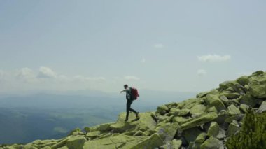 Dev taşlarla kaplı bir dağ yamacı boyunca yürüyen bir adam. Solo turizm. Zor yürüyüş, macera turizmi konsepti.