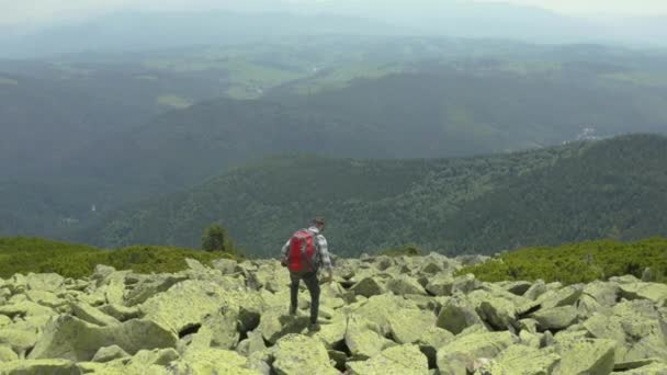 Een Man Loopt Langs Een Berghelling Bedekt Met Gigantische Stenen — Stockvideo