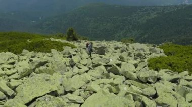 Dev taşlarla kaplı bir dağ yamacı boyunca yürüyen bir adam. Solo turizm. Zor yürüyüş, macera turizmi konsepti.