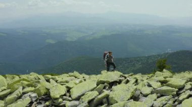 Dev taşlarla kaplı bir dağ yamacı boyunca yürüyen bir adam. Solo turizm. Zor yürüyüş, macera turizmi konsepti.