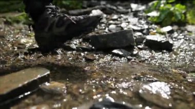 Nehir boyunca dağlara doğru yürüyen bir turistin bacaklarına yakın çekim. Etkin insan seyahat kavramı.