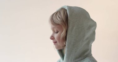 Küçük, yakışıklı bir çocuk. Yakın plan portre. Kapüşonlu uzun saçlı bir çocuk stüdyoda poz veriyor..