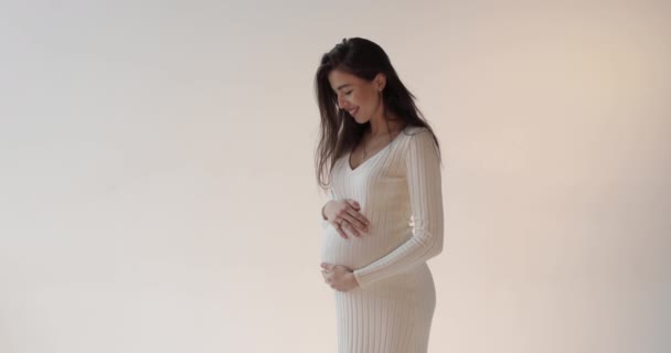 Gyönyörű Terhes Anya Pózol Stúdióban Fehér Háttérrel Egy Fiatal Barna — Stock videók