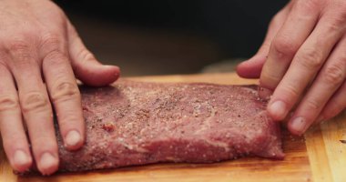 Erkeklerin eline yakın çekim et içine baharat sürterek vahşi doğada pişirmek için hazırlıyorlar. Daha fazla ateşte pişirmek için eti marine ediyorum..