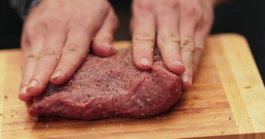 Erkeklerin eline yakın çekim et içine baharat sürterek vahşi doğada pişirmek için hazırlıyorlar. Daha fazla ateşte pişirmek için eti marine ediyorum..