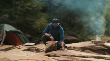 Yalnız bir turist kamp ateşinde yemek pişirir. Erkek yürüyüşçü çölde yürürken çadırın yanında yemek pişirir ve kamp ateşi yakar.