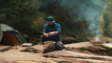Yalnız bir turist kamp ateşinde yemek pişirir. Erkek yürüyüşçü çölde yürürken çadırın yanında yemek pişirir ve kamp ateşi yakar.